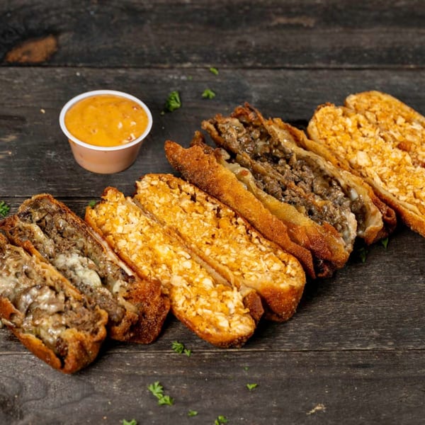 Crispy fried spring rolls, some filled with meat and cheese, others with cheese, alongside a dipping sauce.